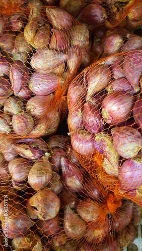 Close up pile of fresh red onions placed together in local market as a background.