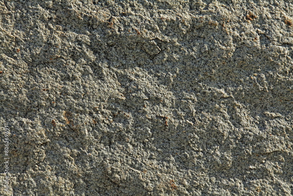 Grey uneven wall, texture, background. Relief rocky and shady surface of granite stone. Roug volcanic rock of light-grey color in urban development and decorative exterior. Granular igneous rock Grey uneven wall, texture, background. Relief rocky and shady surface of granite stone. Roug volcanic rock of light-grey color in urban development and decorative exterior. Granular igneous rock