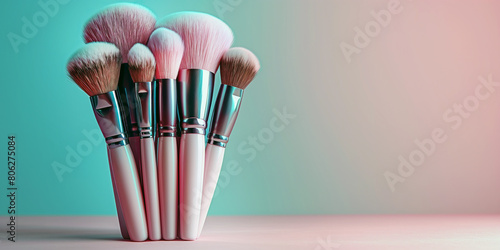 A bundle of soft makeup brushes. Teal and pink background with copy space.