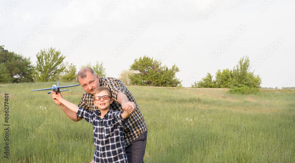 Father and son having fun in the field playing with an airplane