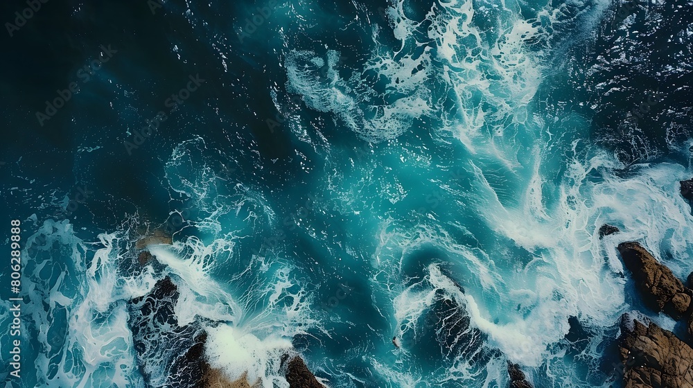 Aerial top view of sea, ocean blue waves crashing on rocky shore