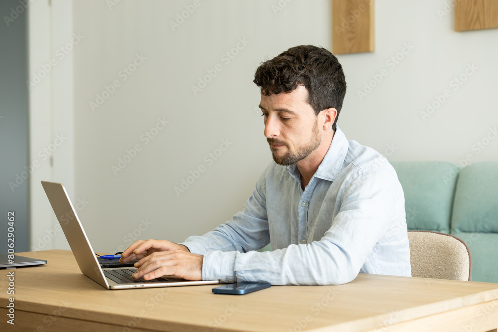 concentrated and serious man typing on the keyboard of his laptop working from home concentrated and serious man typing on the keyboard of his laptop working from home