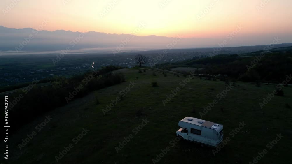 motorhome in a mountain valley, camper on a green meadow at sunrise, aerial shot motorhome in a mountain valley, camper on a green meadow at sunrise, aerial shot
