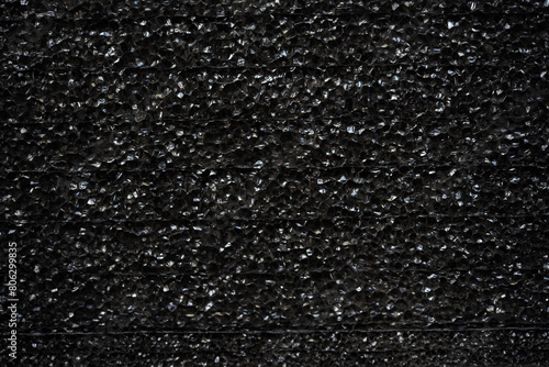Black porous porous foam background. Background texture of black foam rubber photo