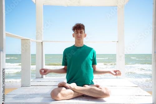 A young attractive student is relaxing by the seashore and doing yoga.