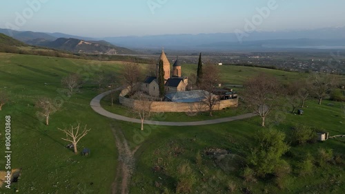 lonely ancient church in the mountains at dawn between green hills, aerial view photo