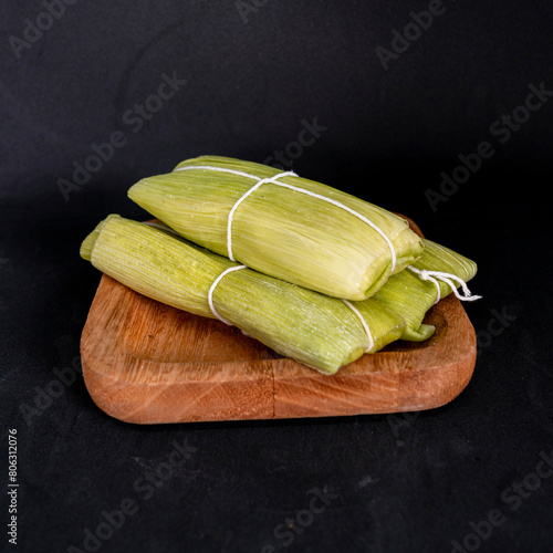 Peruvian sweet humita served on a wooden plate. Black background. photo