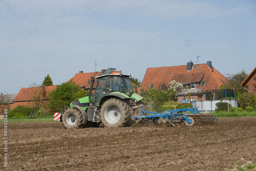 Fototapeta premium Landwirt beim Grubbern eines Feldes