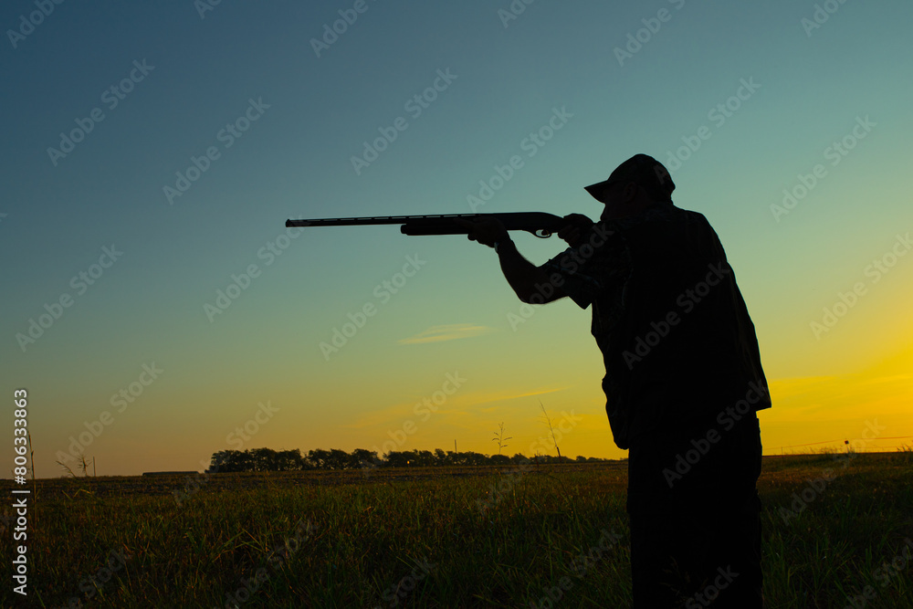 Silhouette of a hunter in a field at sunrise taking aim with a shotgun. Silhouette of a hunter in a field at sunrise taking aim with a shotgun.