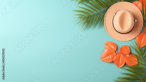 Summer background of A hat, palm leaves, and orange flowers arranged on a blue background