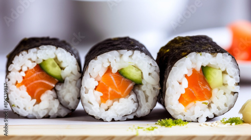 Three sushi rolls with salmon and cucumber on top