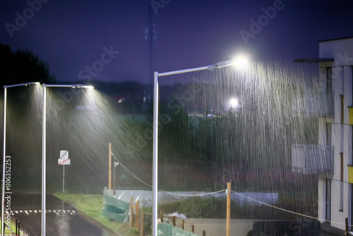 Krople deszczu w świetle ulicznej lampy na osiedlu w mieście.  © FotoDax