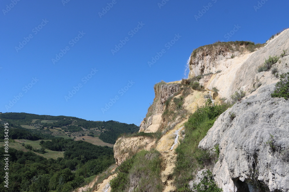 rock with waterfall over tuscan hills rock with waterfall over tuscan hills