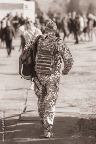 Ukrainian soldier. Male silhouette. Military among civilians. Adaptation of military veterans. Tactical equipment. Military backpack. Term service in the army. Back view.