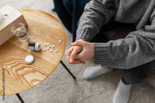 mental health, psychological problem and depression concept - close up of stressed woman hands with sedative medicine or painkiller on table at home