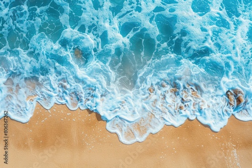 Electric blue waves crashing on sandy shore from an aerial view