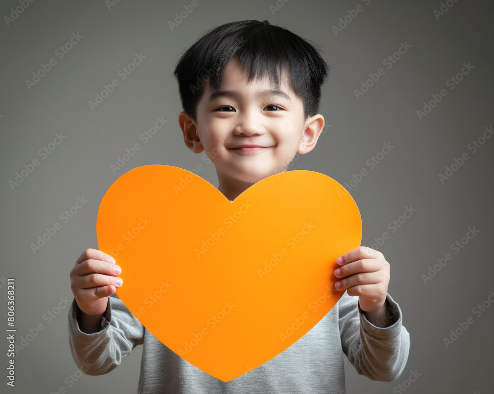 Small Asian boy holding empty orange paper heart in front of him. Generative AI Small Asian boy holding empty orange paper heart in front of him. Generative AI