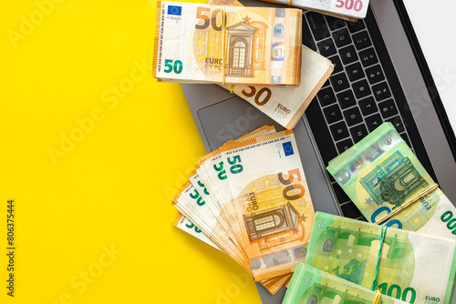 Sport betting app, online bets concept. Laptop with cash stacks on yellow background with copy space top view