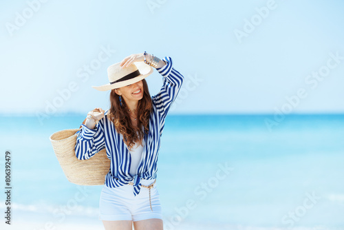 happy elegant woman on seashore with straw bag © Alliance