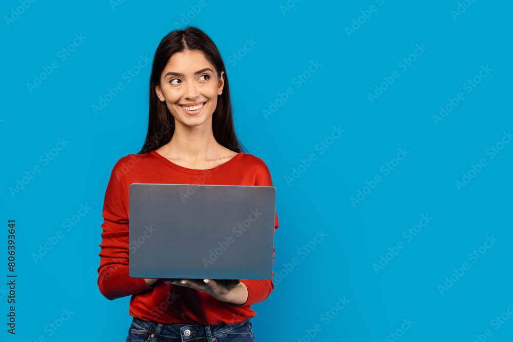 Ταπετσαρία A woman wearing a red shirt is holding a laptop in her hands, displaying a focused expression