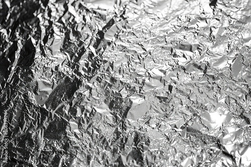 A piece of shiny silver foil with a lot of wrinkles and creases. The foil is crumpled and has a rough texture