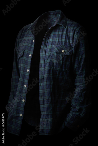 A person wearing a plaid shirt standing in the dark