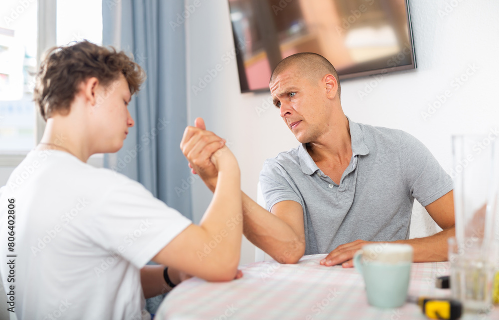 Obraz premium Happy father and son competing in arm wrestling