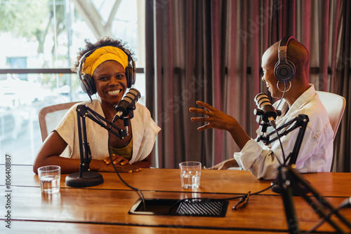 Two happy podcast hosts engaged in a lively conversation in a studio setting