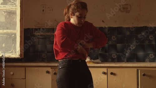 Woman in red does interpretive dance in a rundown kitchen photo