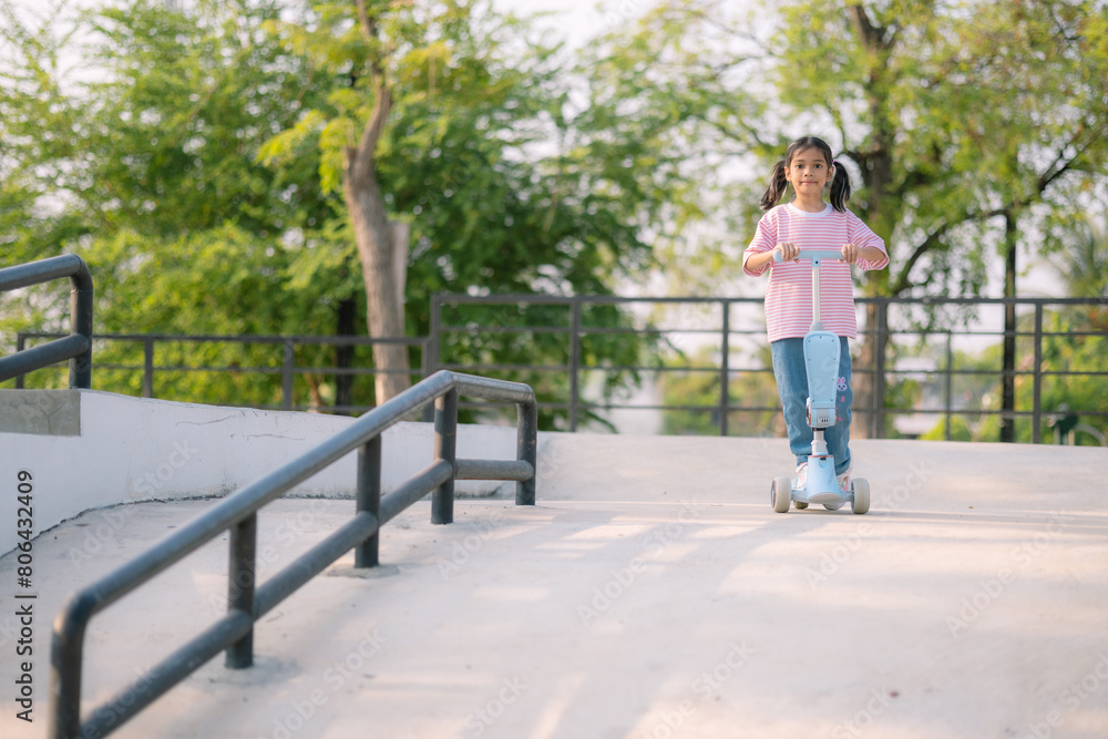 A young girl riding a scooter in a park A young girl riding a scooter in a park