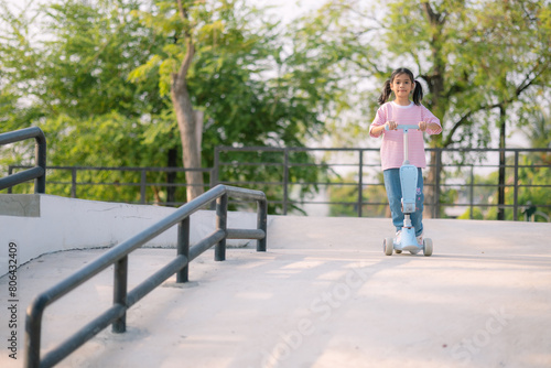 A young girl riding a scooter in a park