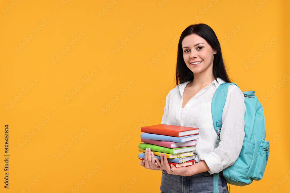 Smiling student with stack of books on yellow background. Space for text Smiling student with stack of books on yellow background. Space for text