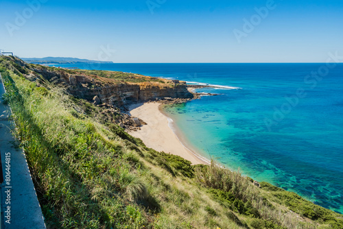 Hill with vegetation with transparent water and sand at Alibabá beach and mountain in horizon, Ericeira - Mafra PORTUGAL