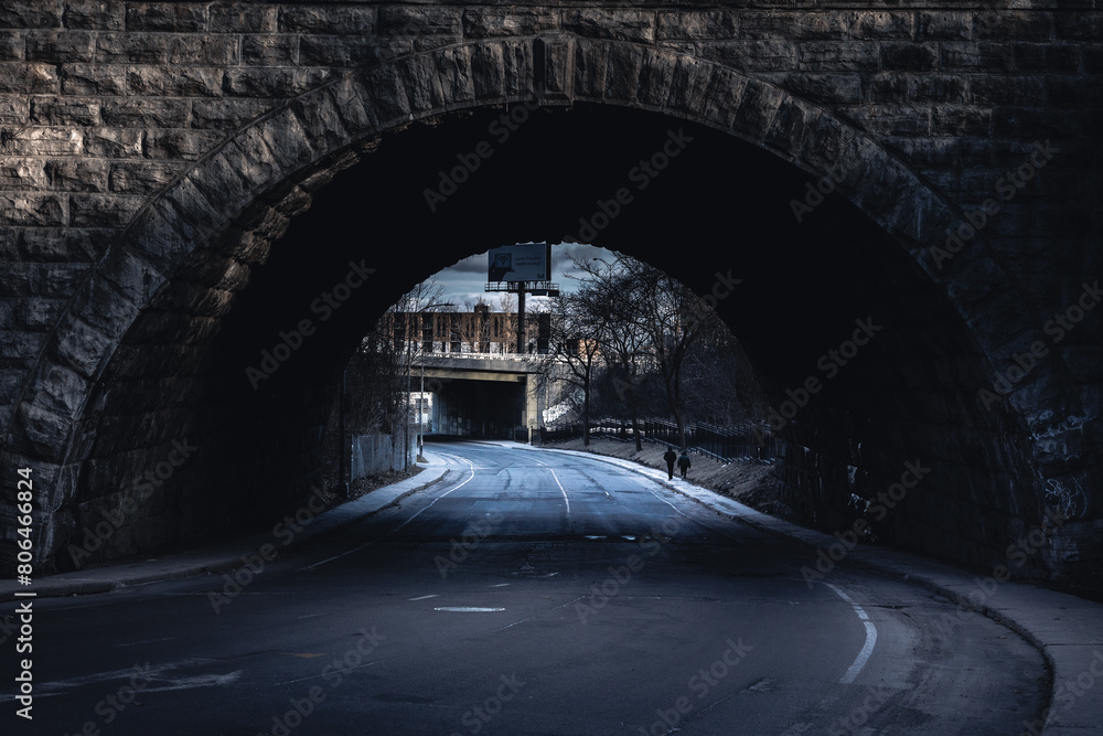 Obraz premium Person walks under dark bridge with tints of monochrome landscape
