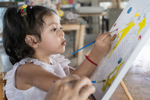  Asian beautiful baby girl drawing on canvas to create creativity happily. I