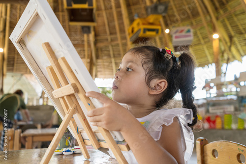Thai baby girl drawing on canvas to create creativity very happy.
