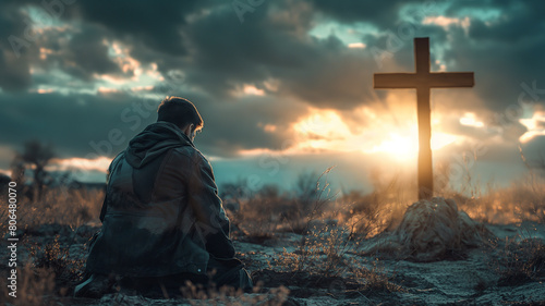 Young man kneeling and looking at the cross. photo