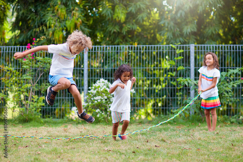 Happy kids play outdoor. Children skipping rope.