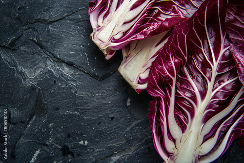 Artistic close-up of radicchio with striking purple leaves and white veins set against a textured dark slate background. photo