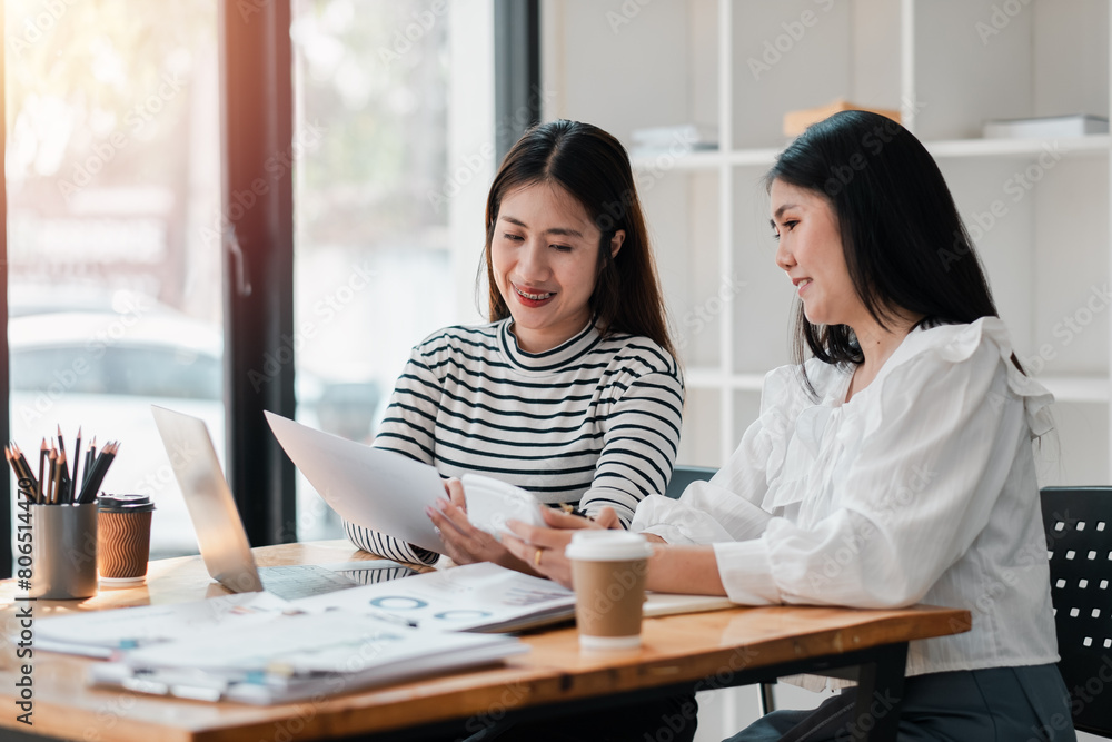 Two engaged female colleagues collaborating on a project, sharing ideas over documents in a well-lit office space. Two engaged female colleagues collaborating on a project, sharing ideas over documents in a well-lit office space.