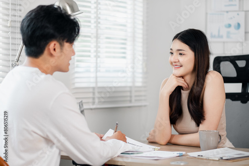 Young woman attentively listens while a man takes notes, both deeply involved in a home office discussion.