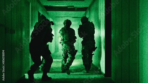 Team of soldiers with guns moving down a corridor night-vision