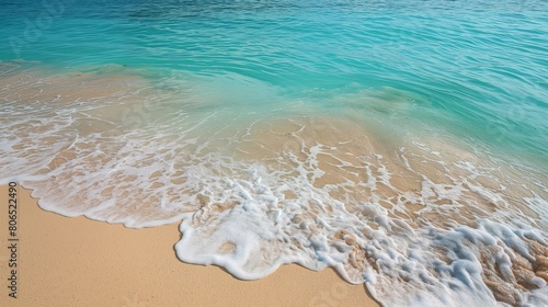 A series of small, gentle waves approaching a sandy beach, their foam creating intricate patterns on the shore, set against a backdrop of a clear, turquoise ocean.
