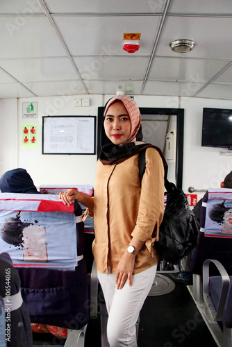 Beautiful Asian woman in hijab standing in public transportation smiling