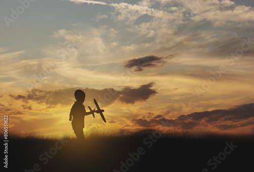 silhouette boy playing toy airplane at sunrise © thekopmylife