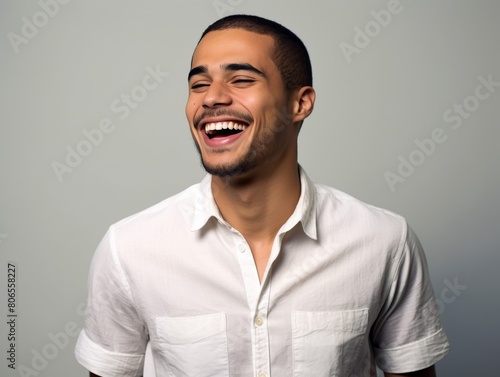 A smiling man in a white shirt is sitting on a blue background