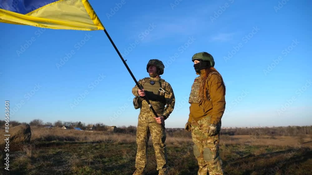 Ukrainian army soldiers stands outdoor at sunset time and waves flag of Ukraine. People in military uniform lifted up flag against blue sky. Victory at war. Resistance to russian invasion. Slow motion Ukrainian army soldiers stands outdoor at sunset time and waves flag of Ukraine. People in military uniform lifted up flag against blue sky. Victory at war. Resistance to russian invasion. Slow motion