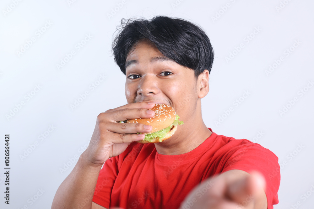 Potrait Of Selfie Excited Young Asian Man Eating Burger Isolated On White Background Potrait Of Selfie Excited Young Asian Man Eating Burger Isolated On White Background