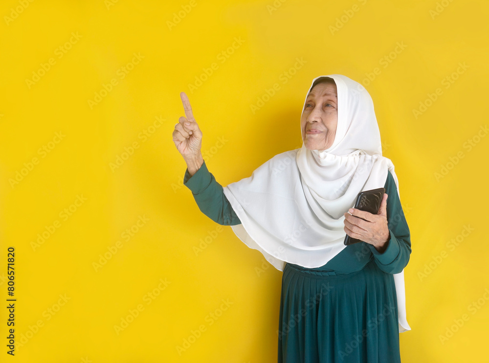 Old Asian Woman Holding Smartphone And Pointing Aside To The Empty Space For Ads Or Text Old Asian Woman Holding Smartphone And Pointing Aside To The Empty Space For Ads Or Text
