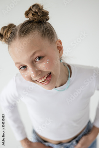 blonde girl with a playful smile shows her tongue at the camera, girl on white phoneme grimaces in front of the camera